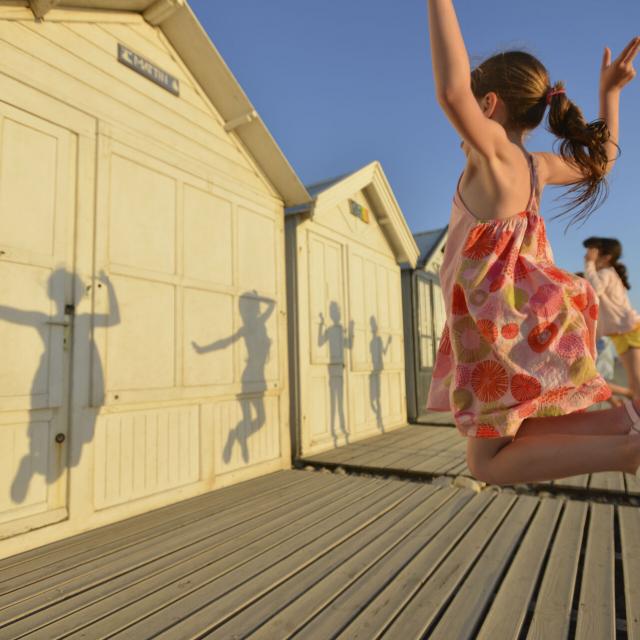 3 Mädchen springen in die Luft vor den Strandhäuschen in Cayeux-sur-Mer, Copyright CRTC Hauts-de-France - Nicolas Bryant