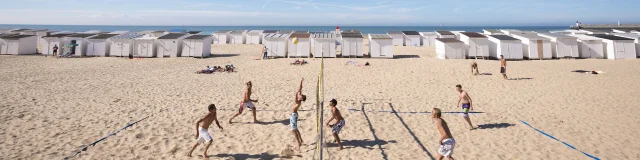 Calais. La plage de Calais avec ses cabines de plage, son port et des joueurs de beach-volley